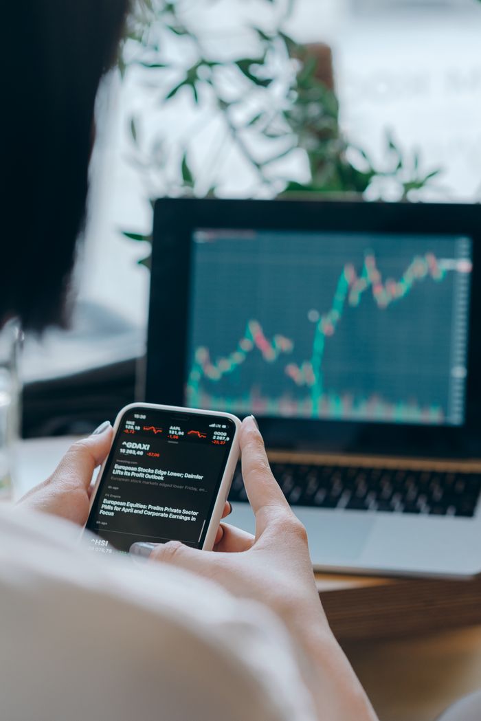 services-04 Person using smartphone for stock market analysis at home office.